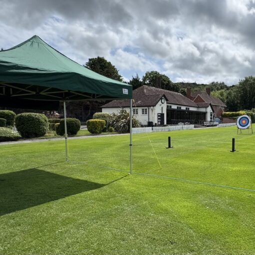 Outdoors st a field with a pavilion in the background and archery targets in the mid ground